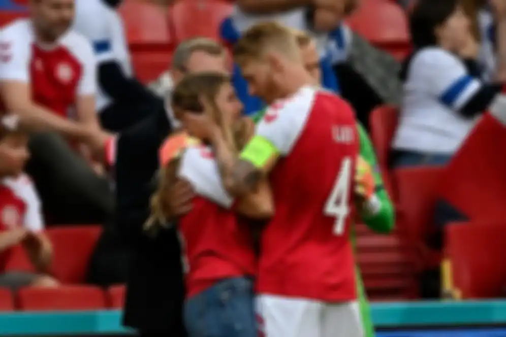 Bersama kiper Denmark, Kasper Schmeichel, kapten tim Simon Kjaer menecoba menenangkan Sabrina Kvist Jensen, istri Christian Eriksen. 