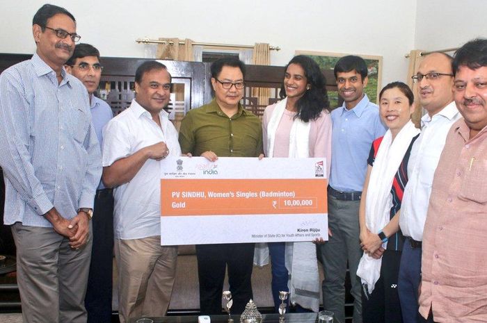 Atlet bulu tangkis asal India, PV Sindhu, menerima uang hadiah senilai Rs 10 lakh atau setara Rp 200 juta rupiah dari Menteri Olahraga India, Kiren Rijiju, seusai kemenangannya di Kejuaraan Dunia BWF 2019.