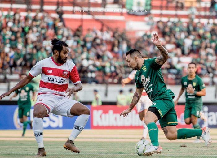 Pemain Persebaya, Damian Lizio (kanan), berebut bola dengan bek Madura United, Fandry Imbiri (kiri) pada laga leg pertama babak 8 besar Piala Indonesia 2018 di Stadion Gelora Bung Tomo, Rabu (19/6/2019).