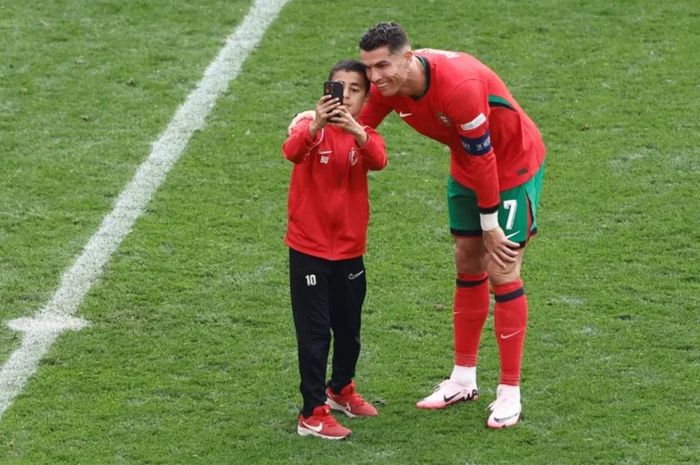 Cristiano Ronaldo melayani permintaan swafoto (selfie) dari seorang bocah yang masuk ke lapangan dalam laga Euro 2024 antara Turkiye dan Portugal di Westfalenstadion, Dortmund, 22 Juni 2024.