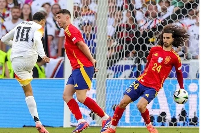 Bola tembakan keras gelandang Timnas Jerman Jamal Musiala membentur tangan bek Spanyol Marc Cucurella dalam perempat final Euro 2024. Seusai laga itu, UEFA menyebut bukan penalti, tapi kini menyatakan sebaliknya.