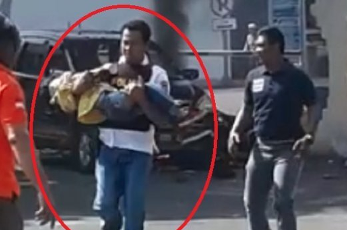 Seorang polisi menyelamatkan anak kecil usai ledakan bom di Polrestabes Surabaya.
