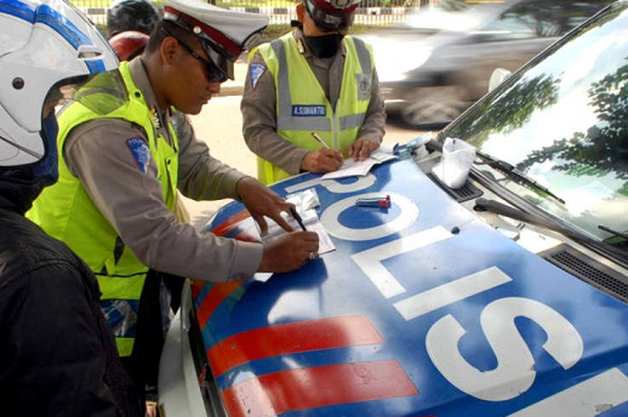 Ilustrasi polisi sedang bertugas memberikan surat tilang.