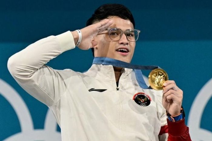 Rizki Juniansyah memperlihatkan medali emasnya seusai memenangi final angkat besi kelas 73 kg di Olimpiade Paris 2024.