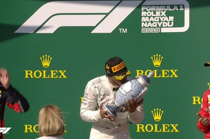 Pembalap Mercedes, Lewis Hamilton (tengah) mencium trofi setelah menjadi juara Formula 1 GP Hungaria di Hungaroring, Minggu (4/8/2019).