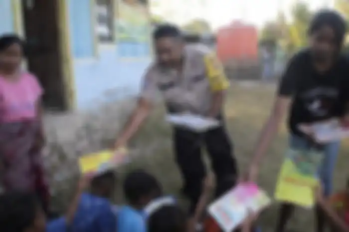 Aipda Abraham membagikan buku bacaan kepada sejumlah anak di Desa Kabulak, NTT.