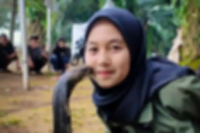 Aulia Khairunnisa saat bermain bersama ular King Cobra yang dipeliharanya sejak kecil. Ular ini diberi nama Rambo.