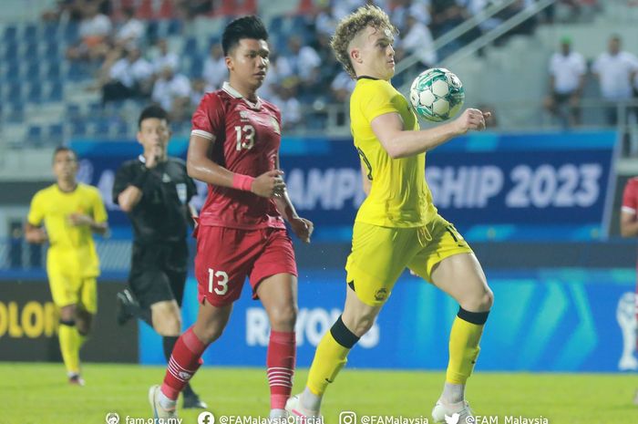 Pemain Malaysia, Fergus Tierney (kanan), saat berduel dengan bek Timnas U-23 Indonesia, Kadek Arel (kiri).