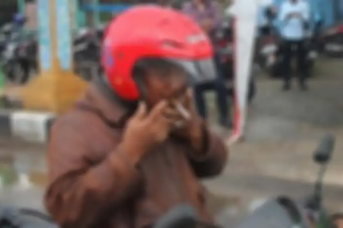 Pemotor dilarang merokok saat naik motor, bisa kena denda Rp 750 ribu.