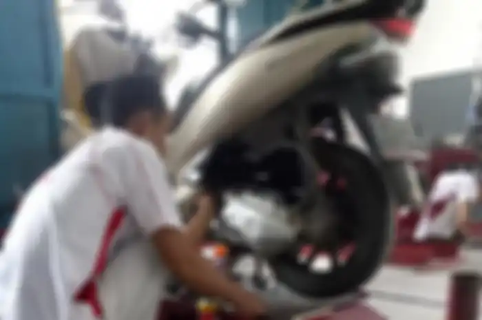 Mekanik bengkel resmi sedang menyervis motor Honda PCX 150.