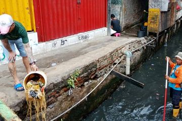 Seorang warga membuang sampah di kali di depan PPSU. 