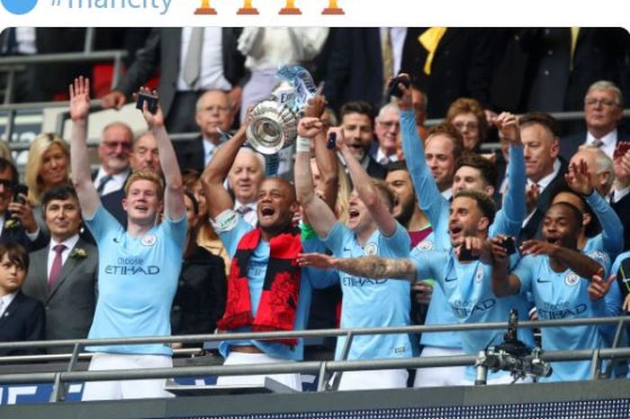 Kapten Manchester City, Vincent Kompany, mengangkat trofi Piala FA usai mengalahkan Watford dalam laga final di Stadion Wembley, Sabtu (18/5/2019).