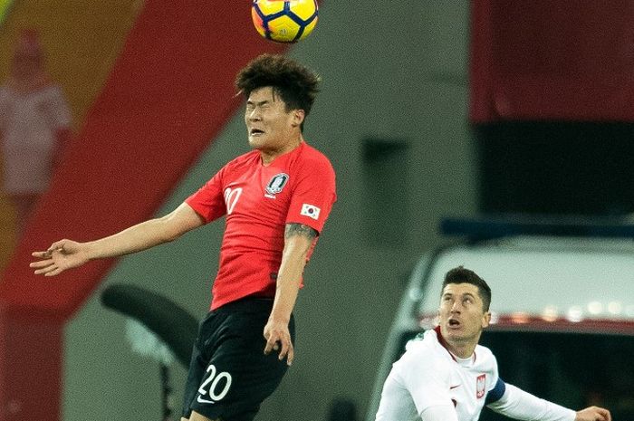 Kim Min-jae (kiri) menyundul bola dekat Robert Lewandowski dalam duel uji coba timnas Korea Selatan lawan Polandia di Chorzow (27/3/2018).