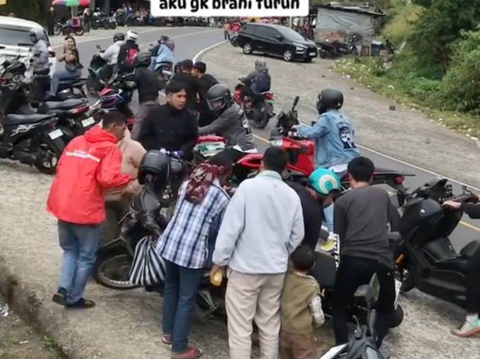 Warga bahu-membahu membantu Desta membangunkan mogenya yang menimpa motor warga.
