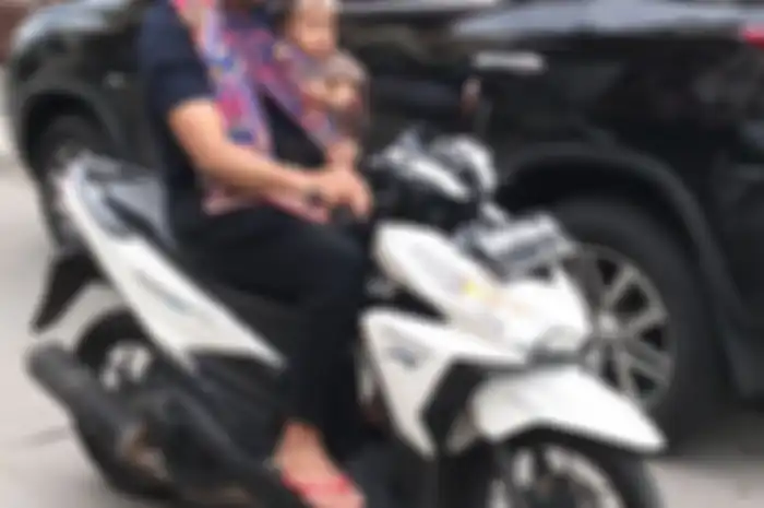 Kaos oblong mengenakan sendal jepit bawa motor, gaya pengendar motor biasa saja. Padahal dia itu pen