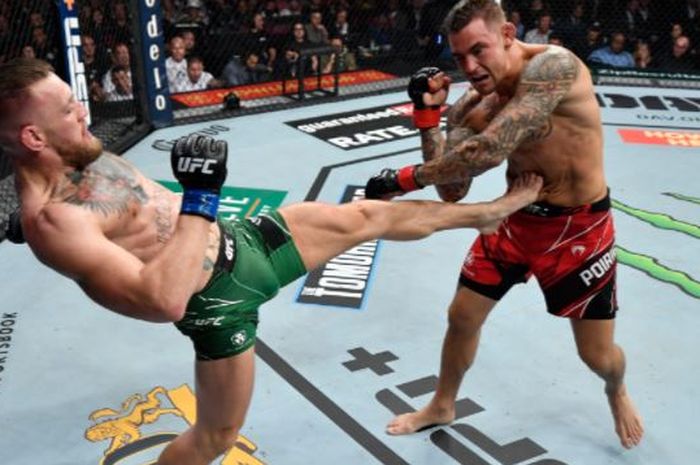 Conor McGregor (kiri) saat melakukan tendangan untuk menyeranga Dustin Poirier pada duel trilogi pada UFC 264 di T-Mobile Arena, Las Vegas, Nevada, AS, Minggu (11/7/2021).