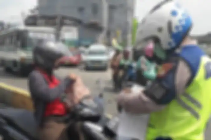 Ilustrasi polisi melakukan tilang manual terhadap pemotor.