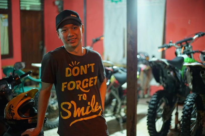 Kevin Sanjaya berpose di belakang motor trail.