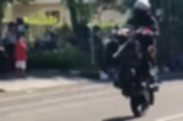 Anggota polisi pamer aksi wheelie di jalan raya.