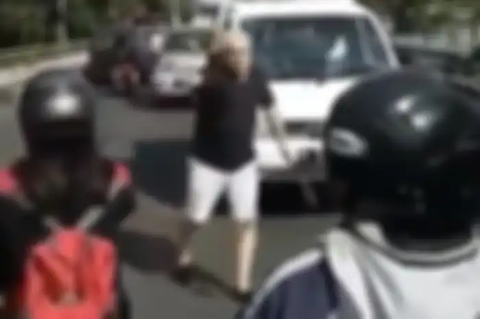 Seorang bule membantu pemotor dan pengendara mobil di Bali.