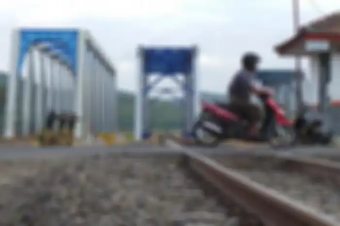 Pengendara motor melintasi rel kereta api