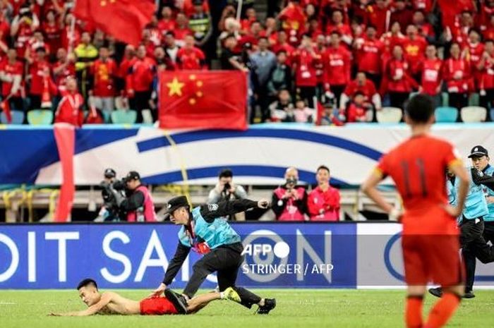 Petugas keamanan menangkap suporter yang menerobos masuk ke lapangan dalam laga Timnas China melawan Jepang di ajang Kualifikasi Piala Dunia 2026.