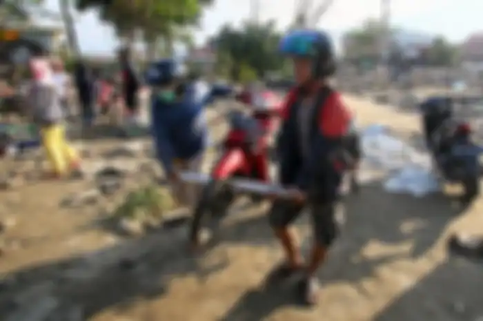 Sejumlah warga mengevakuasi motor pasca kejadian gempa dan tsunami di Donggala, Palu, Sulsel.