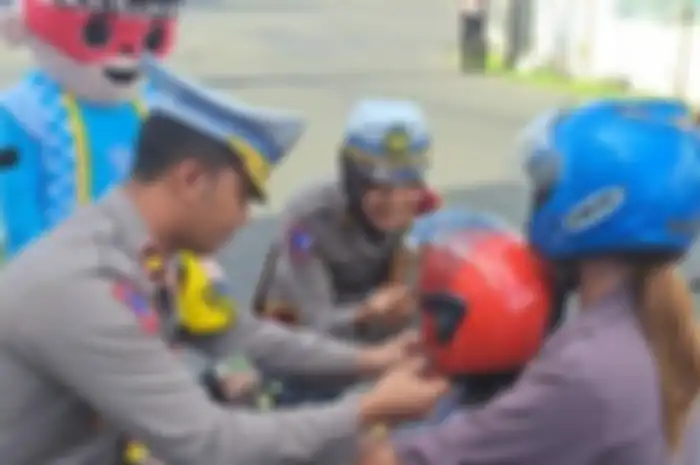 Polisi memberikan coklat dan helm kepada anak dari pengendara dalam momen Valentine Day.