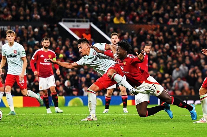 Aksi bek FC Twente berdarah Indonesia, Mees Hilgers, menjatuhkan Kobbie Mainoo dalam laga melawan Manchester United pada matchday 1 Liga Europa 2024-2025 di Stadion Old Trafford, Rabu (25/9/2024).