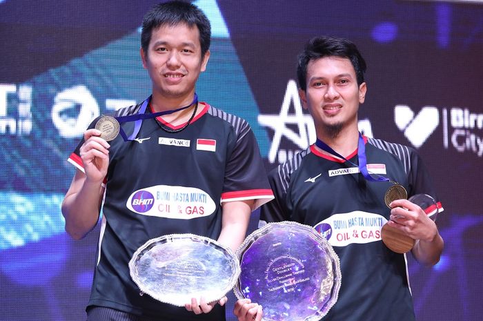 Pasangan ganda putra Indonesia, Mohammad Ahsan/Hendra Setiawan, berpose dengan medali dan trofi juara All England Open 2019 di atas podium kampiun di Arena Birmingham, Birmingham, Inggris, Minggu (10/3/2019).