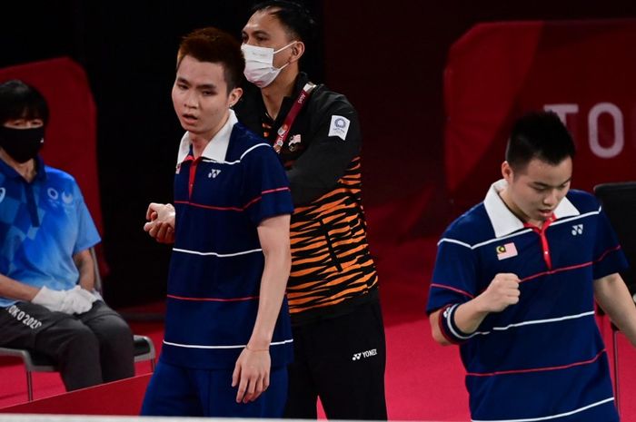 Pasangan ganda putra Malaysia, Soh Wooi Yik (kiri) dan Aaron Chia, bersama pelatih,  Flandy Limpele, bereaksi setelah kemenangan atas Marcus Fernaldi Gideon/Kevin Sanjaya Sukamuljo (Indonesia) pada perempat final Olimpiade Tokyo 2020 di Musashino Forest Sports Plaza, Tokyo, Jepang, 29 Juli 2021.