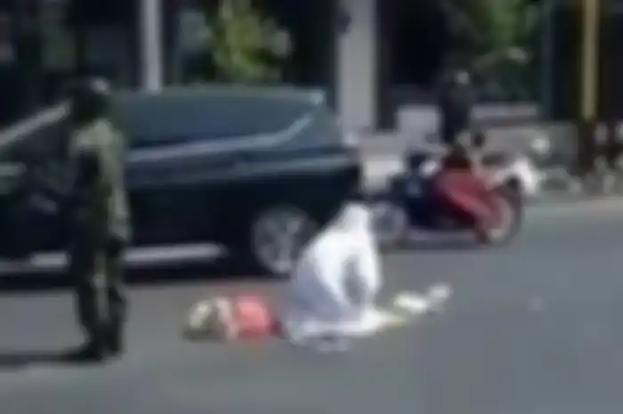 seorang wanita lakukan gerakan sholat di tengah perempatan jalan dengan dijaga seorang TNI di daerah