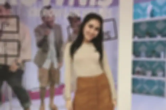 Ayu Ting Ting memadukan kaus lengan panjang dengan rok mini berwarna cokelat beraksen button dari bahan suede