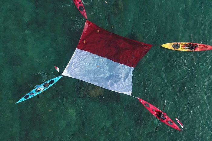 Pengibaran bendera Merah Putih di atas air laut Pantai Kalicaa, Tanjung Lesung, Banten, oleh atlet kayak, Sabtu (17/8/2019).