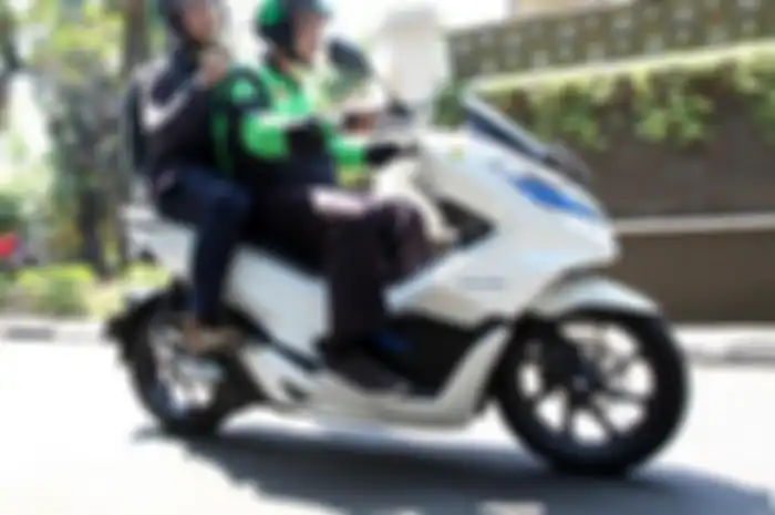 Ilustrasi driver Gojek naik motor listrik.