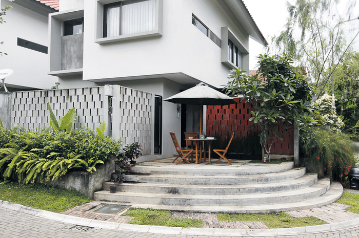 Rumah yang terletak di sudut ini memiliki fasad yang unik. Pagar terbuat dari beton aerasi ditata unik membentuk rongga geometris. Di teras depan inilah sang pemilik juga para tamu senang berkumpul sambil melihat anak-anak yang bermain di taman terbuka.