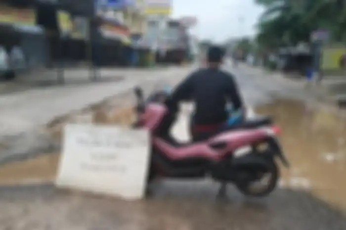 Pemotor memarkirkan Yamaha NMAX di tengah jalan sambil memancing.
