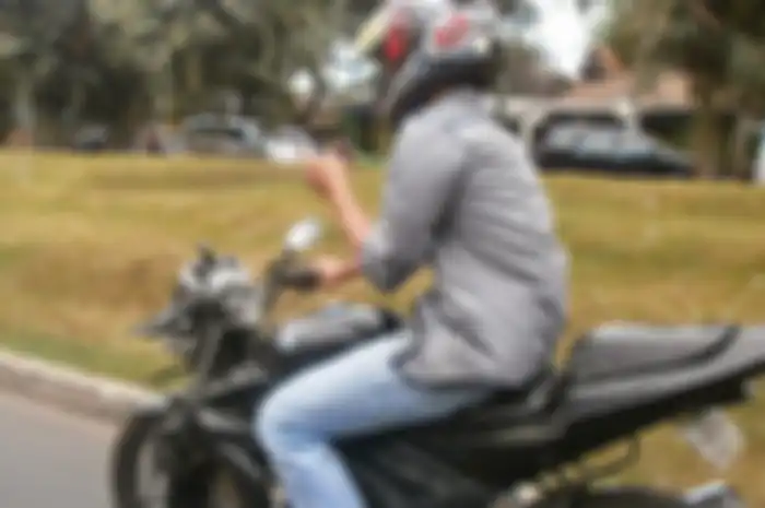 Ilustrasi pengendara motor main ponsel dan pakai headset.