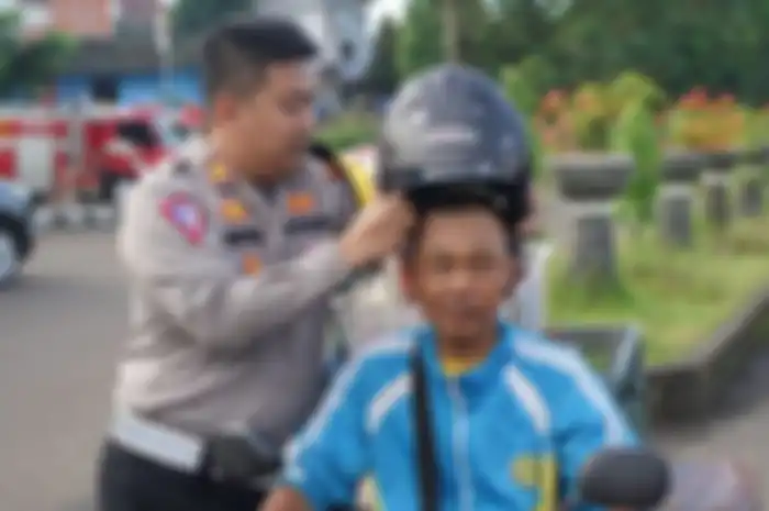 Petugas Satlantas Polres Sukabumi memberikan helm kepada pemotor yang melanggar lalu lintas.