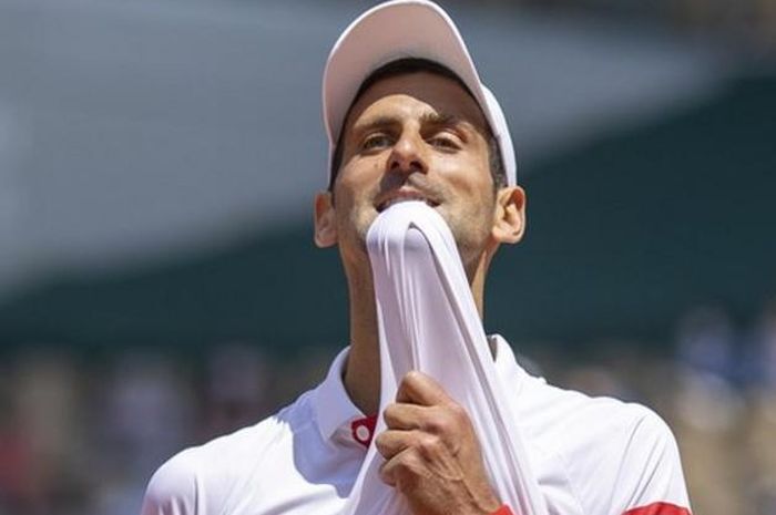 Petenis tunggal putra nomor satu dunia asal Serbia, Novak Djokovic, menggigit kaosnya saat menjalani pertandingan melawan Lorenzo Musetti (Italia) pada babak keempat French Open 2021. Djokovic menang dengan skor 6-7(9), 6-7(7), 6-1, 6-0, 4-0 di lapangan Philippe Chatrier, Roland Garros, Paris, Pranc