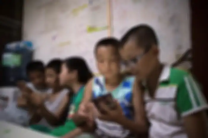 Ilustrasi anak-anak bermain game di ponsel.