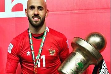 Pemain timnas Palestina, Mohammed Rashid, mengenakan jersey timnas Indonesia saat mengangkat trofi Piala Palestina.