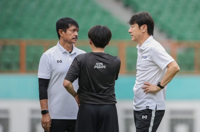 Dua pelatih berlabel Timnas Indonesia, Indra Sjafri (kiri) dan Shin Tae-yong (kanan), tengah berbincang satu sama lain.