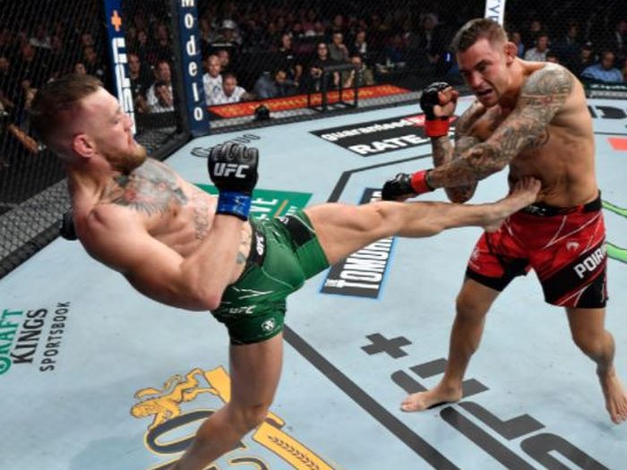 Conor McGregor (kiri) saat melakukan tendangan untuk menyeranga Dustin Poirier pada duel trilogi pada UFC 264 di T-Mobile Arena, Las Vegas, Nevada, AS, Minggu (11/7/2021).