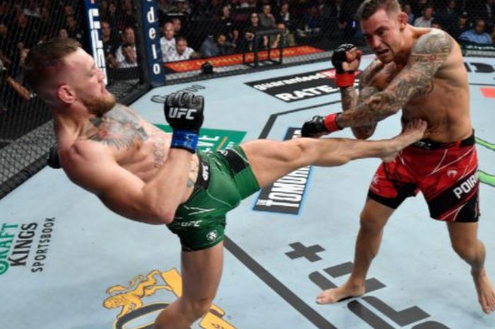 Conor McGregor (kiri) saat melakukan tendangan untuk menyeranga Dustin Poirier pada duel trilogi pada UFC 264 di T-Mobile Arena, Las Vegas, Nevada, AS, Minggu (11/7/2021).