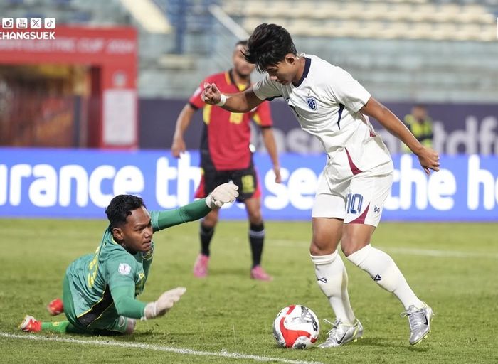 Aksi pemain Thailand, Suphanat Mueanta, berhadapan dengan kiper Timor Leste,  Junildo Pereira, pada matchday pertama Grup A ASEAN Cup 2024 di Stadion Hang Day, Hanoi, Minggu (8/12/2024).