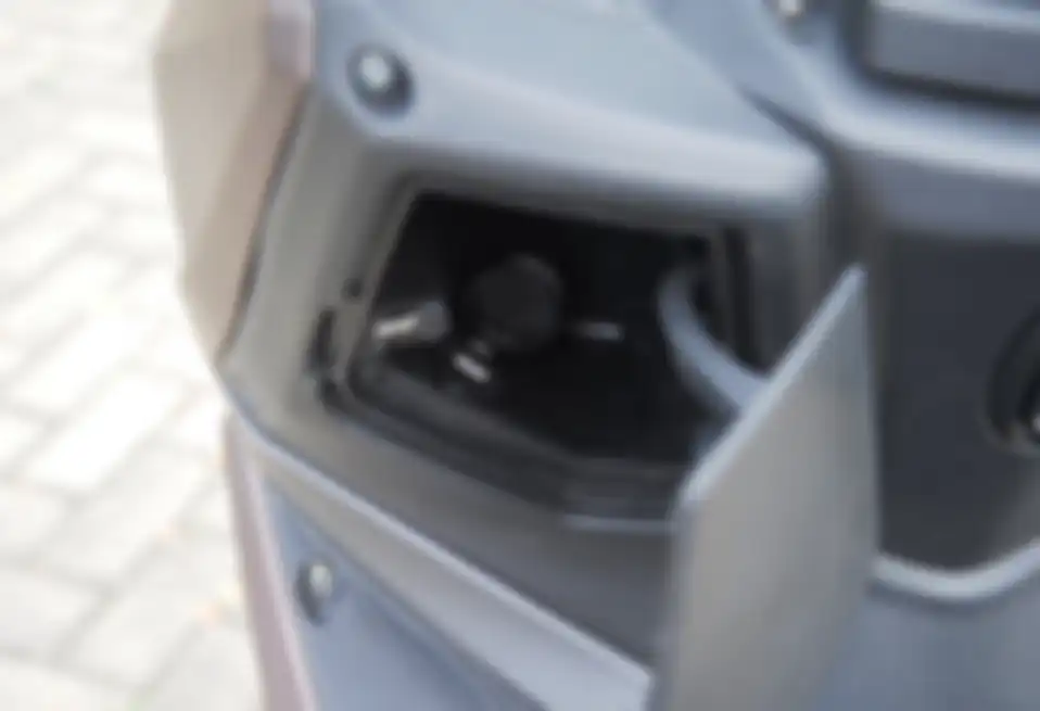 Di bawah setang kiri SYM Jet 14 ada konsol, di dalamnya terdapat power outlet