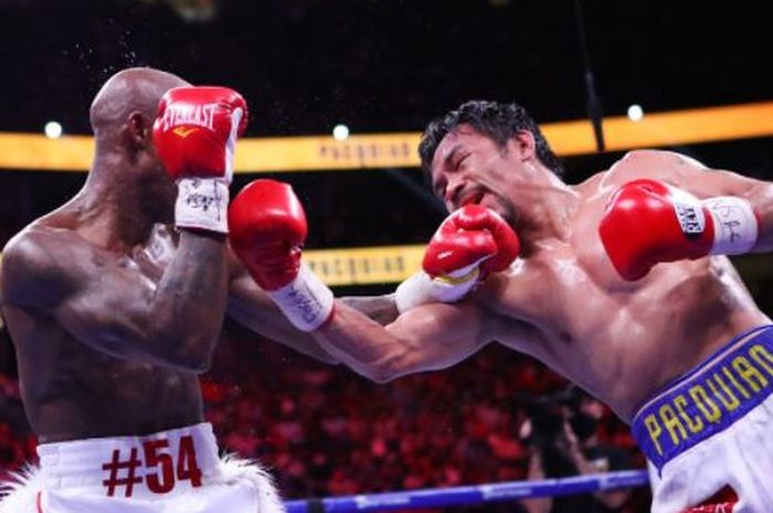 Yordenis Ugas (kiri) saat menerima pukulan dari Manny Pacquiao (kanan) ketika bertarung di T-Mobile Arena, Las Vegas, Nevada, Amerika Serikat, Sabtu (21/8/2021).