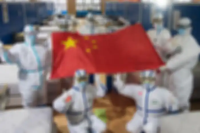 Sejumlah tenaga media di Wuhan, Hubei, berpose dengan membentangkan bendera China di sebuah tempat perawatan yang sudah tanpa pasien Covid-19.
