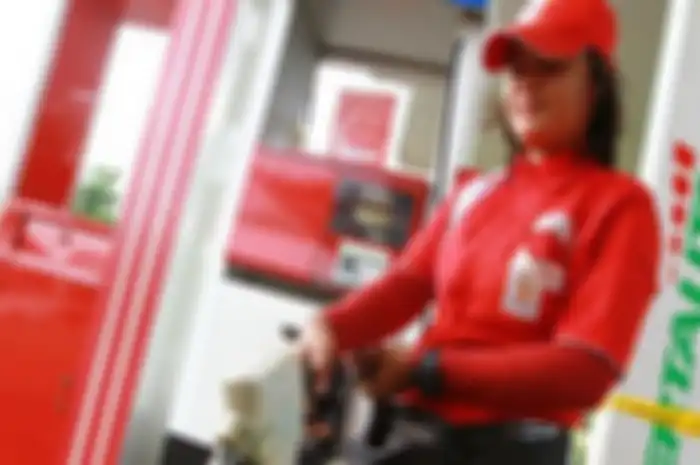 Ilustrasi petugas SPBU mengisikan Pertalite ke motor.